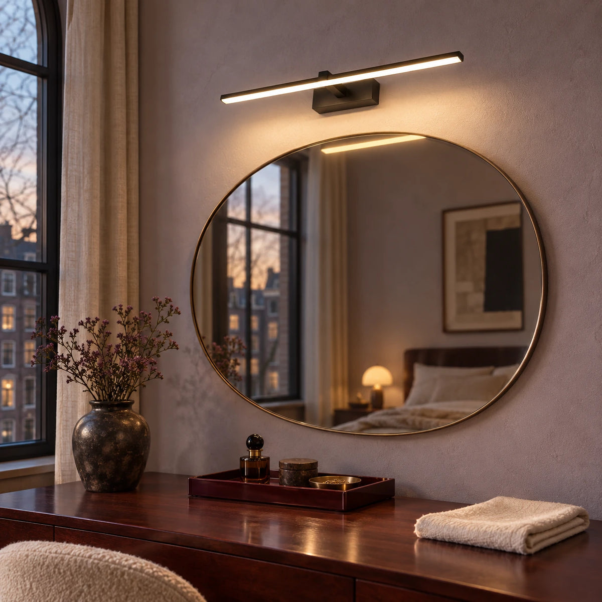 Black linear wall light above a bedroom dressing mirror in a muted lavender room
