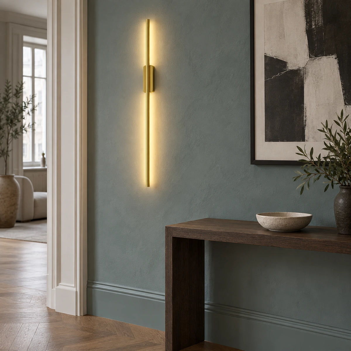 Gold vertical wall light beside an oak console in a blue-green entrance
