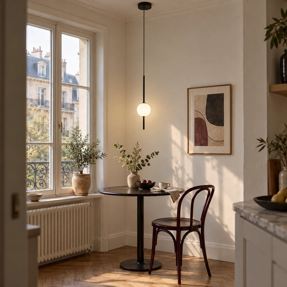 Single black globe-drop pendant over a compact breakfast table in a European apartment