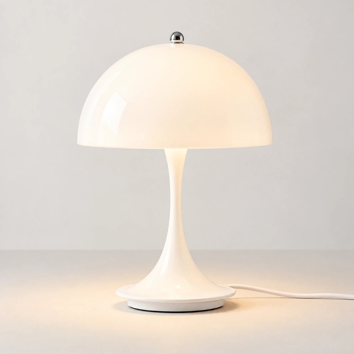 White dome table lamp with tapered base and visible power cord, studio view