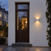 Small white cube wall light beside a complete timber and glass entrance door at dusk