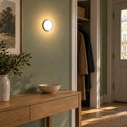 Small circular wall sconce on a sage hallway wall above an oak console
